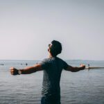 photo of man wearing gray shirt near sea