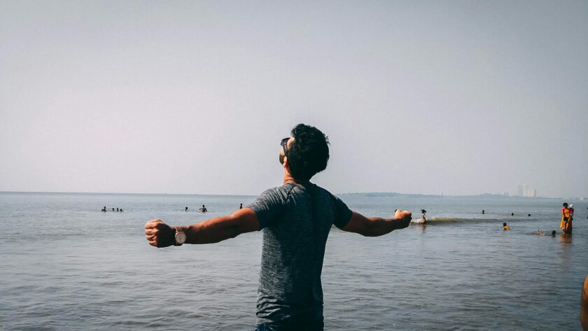 photo of man wearing gray shirt near sea